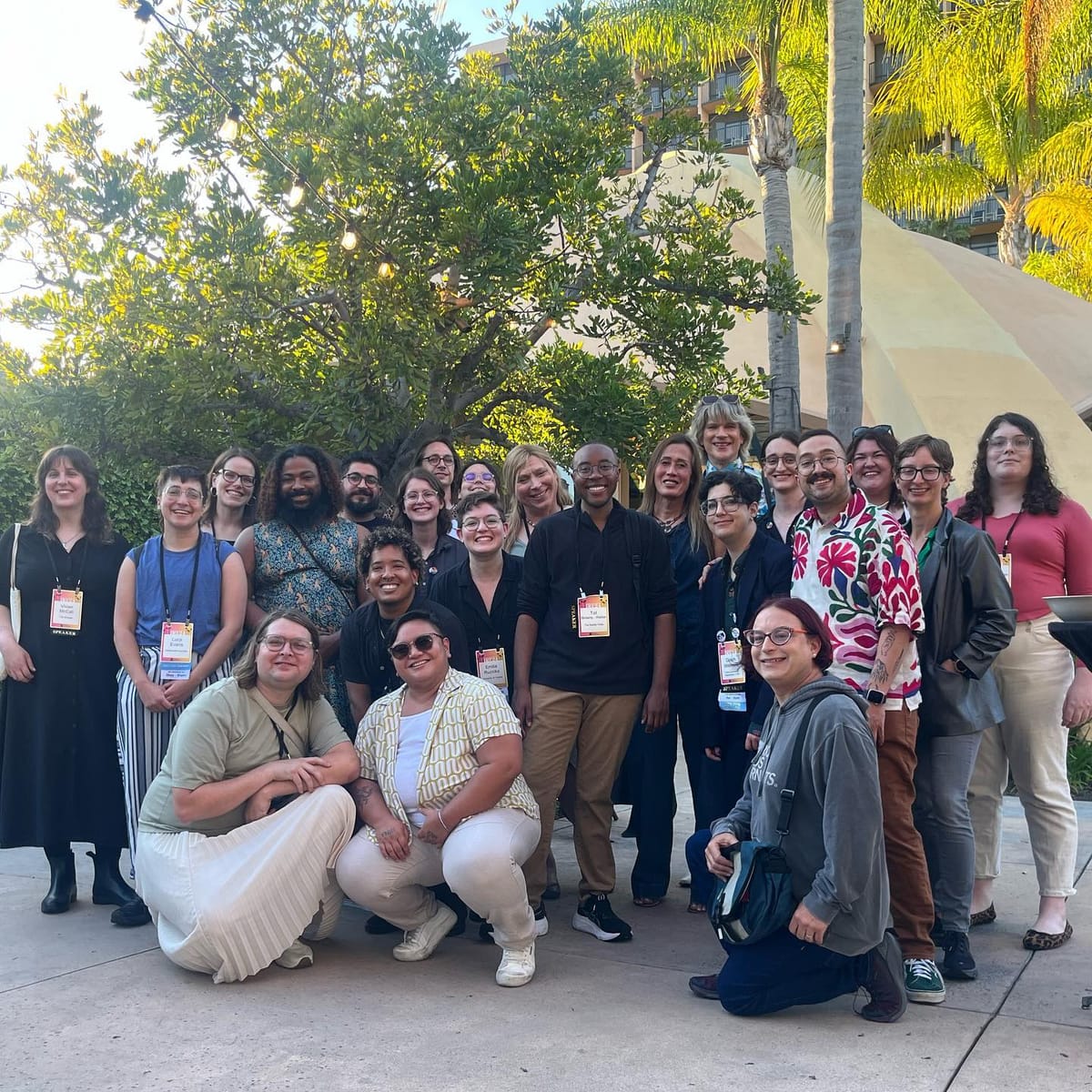 Two-dozen gender-diverse journalists pose in front of California trees.